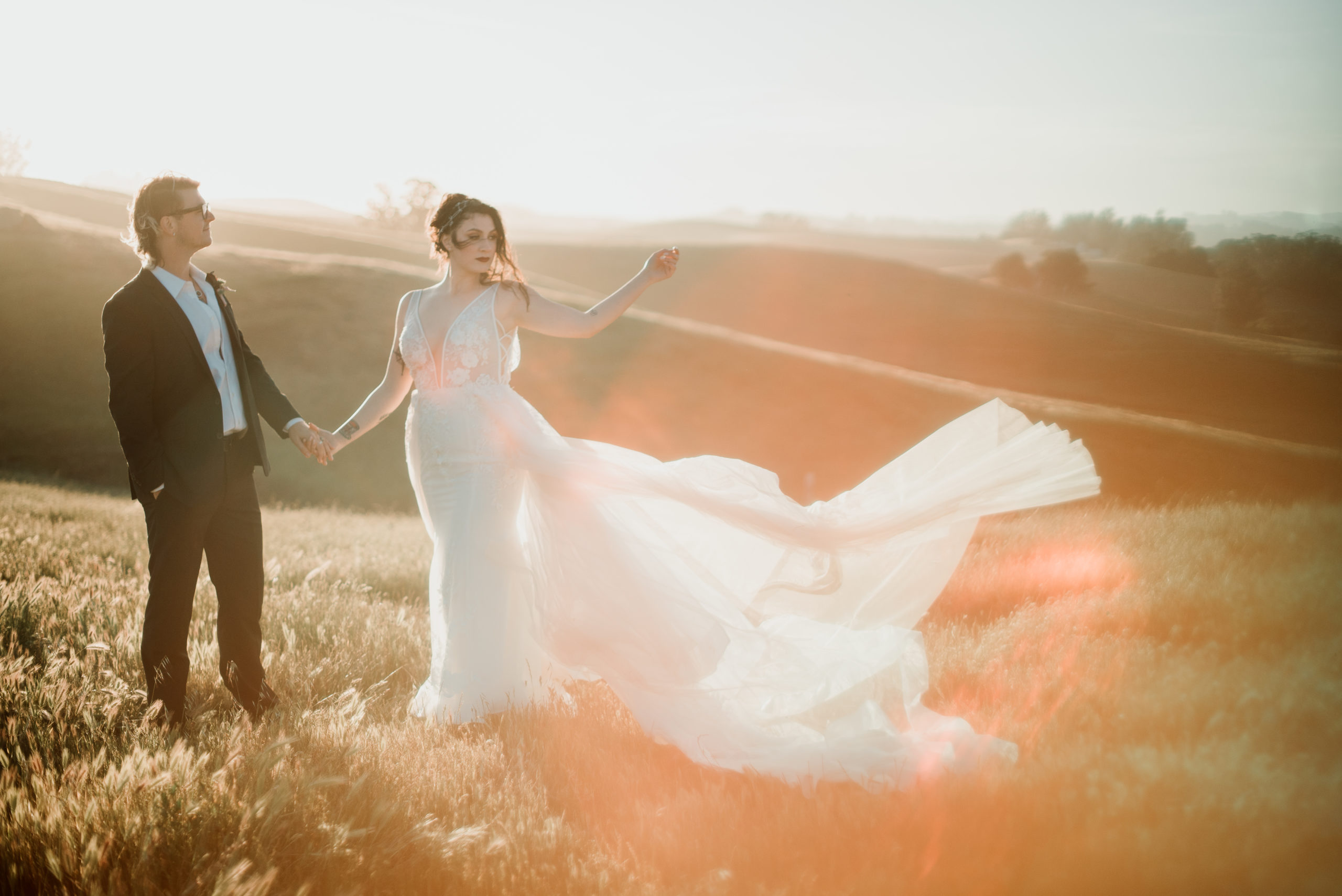 Bride and groom on the mountain top with her dress blowing in the wind