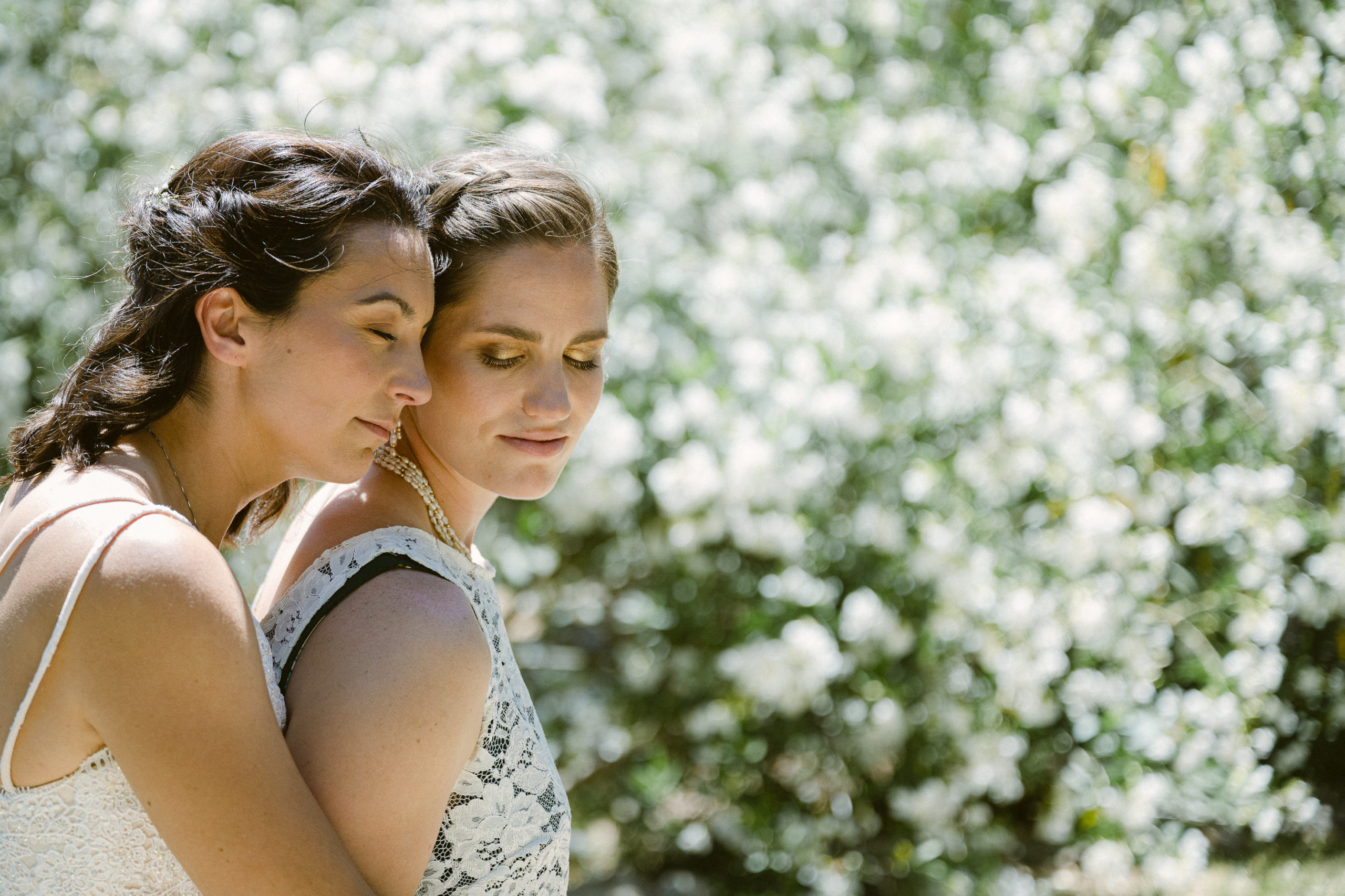 Bride and bride hold each in front of flowers