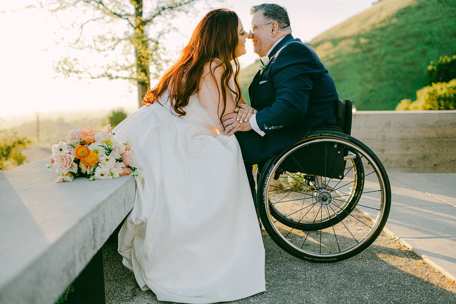 Bride siting and groom in a wheel chair kiss