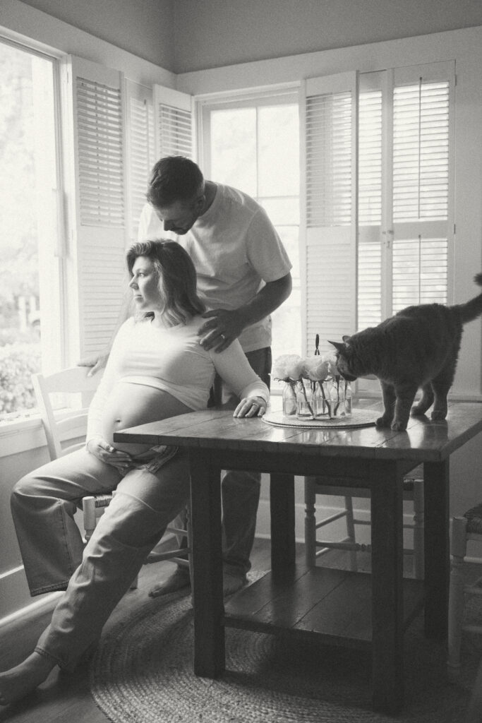 Intimate at-home maternity session with cozy setting and cat in kitchen window

