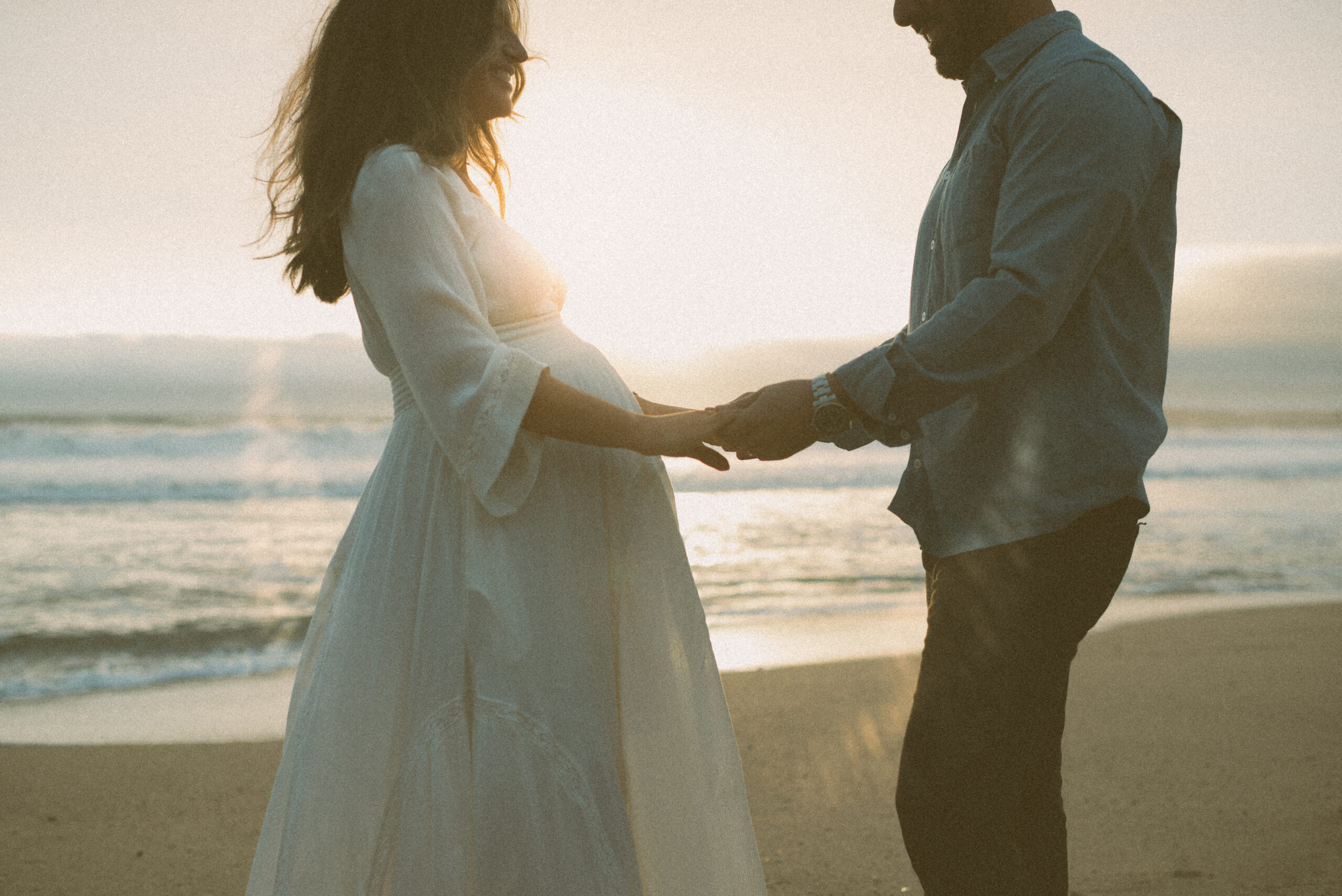 Outdoor maternity portrait in golden hour half moon bay beach with flowing dress