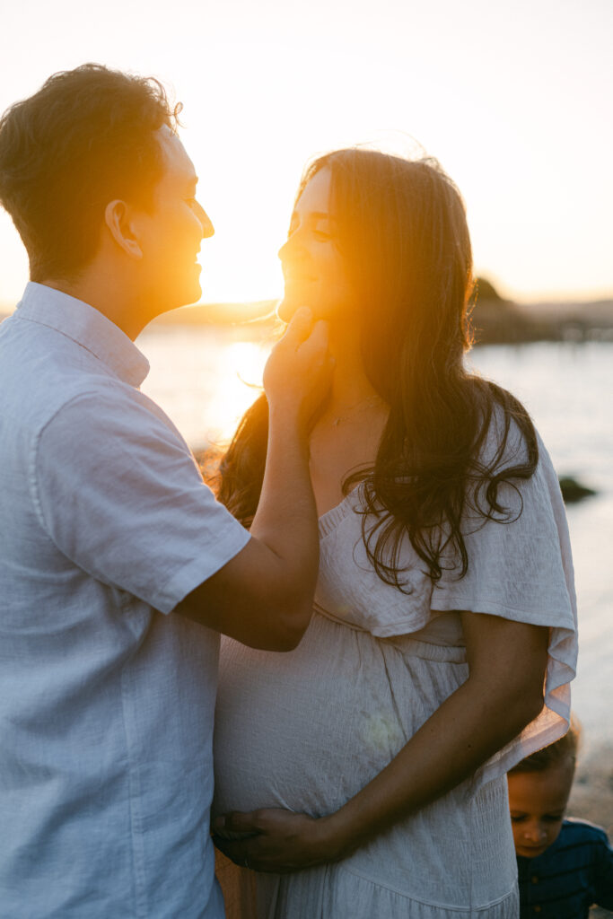 Golden light streams through mom and dad at bay area beach maternity session
