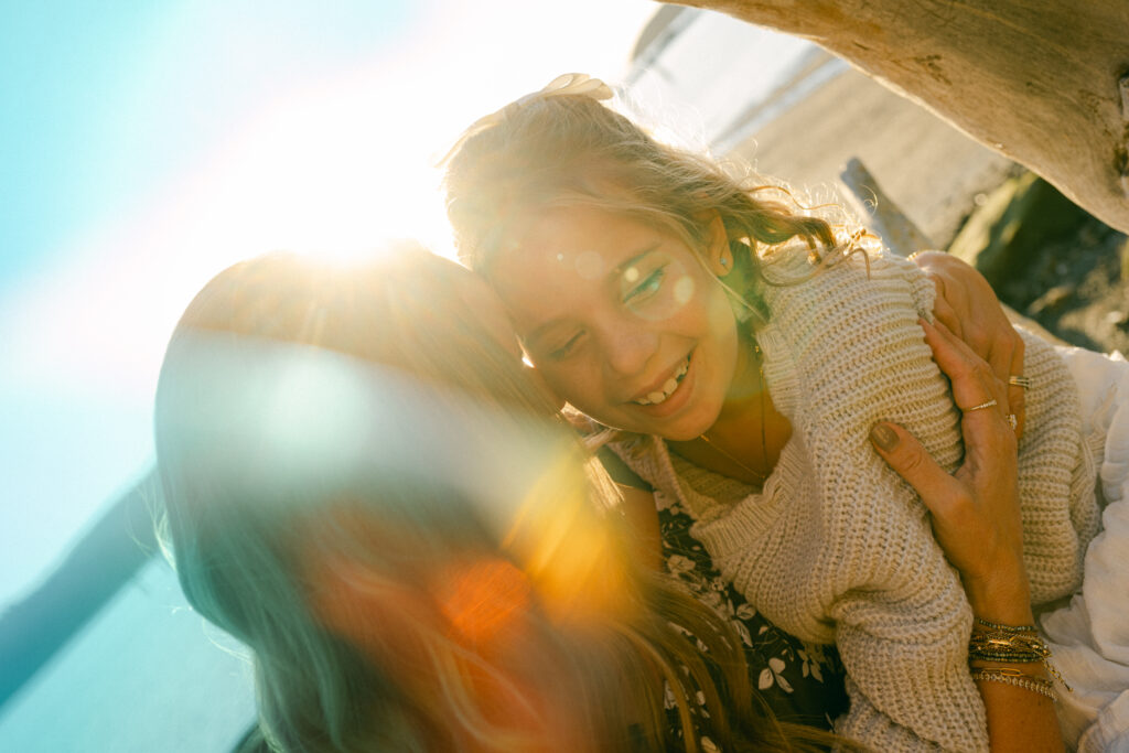 mother hugging child in warm sunset light during candid outdoor family photography session
