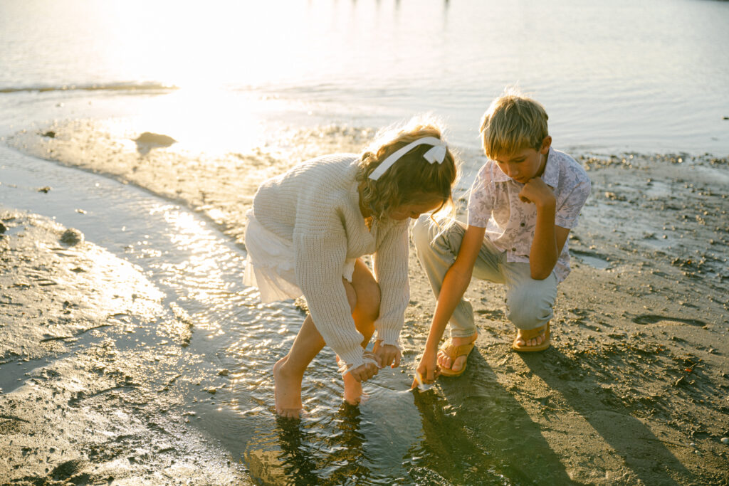 two children playing at water’s edge on beach during golden hour family photography session